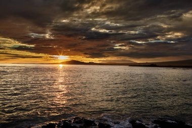 Galapagos Adaları üzerinde gün batımı nefes kesici bir doğa manzarasıdır. Güneş ufka doğru batarken, gökyüzü parlak renkli portakallar, koyu mor renkler ve pürüzsüz harmanlanmış yumuşak pembelerden oluşan bir tuvale dönüşür.. 