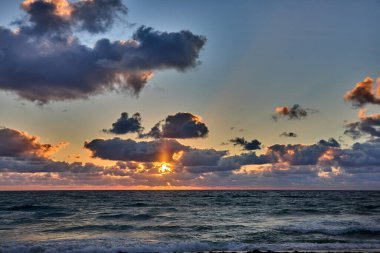 Okyanusun gökyüzüyle buluştuğu kumlu bir sahilde ilk yürüyüşler. Delray Sahili Florida.