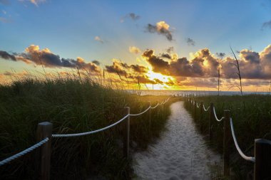 Okyanusun gökyüzüyle buluştuğu kumlu bir sahilde ilk yürüyüşler. Delray Sahili Florida.