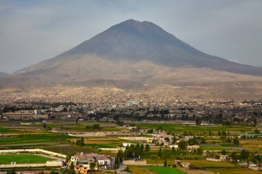 Güneş And Dağları 'nın arkasında batarken Beyaz Şehir, sessiz bekçiler Misti, Chachani ve Pichu Pichu tarafından çerçevelenmiş yumuşak kehribar ışıklarıyla parıldıyor.