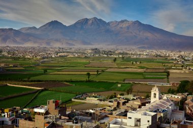 Arka planda yanardağ sisi ve Chachani olan Arequipa yakınlarındaki tarım arazileri..