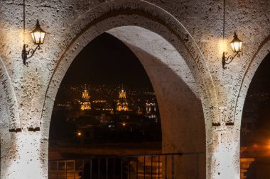 Gece gökyüzünün altında, Yanahuaras kemerleri Arequipa 'nın parlayan kalbini çerçeveler. Şehir ışıkları aşağıda parıldarken, sessiz volkanlar izliyor..