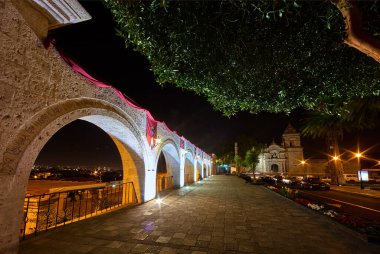 Gece gökyüzünün altında, Yanahuaras kemerleri Arequipa 'nın parlayan kalbini çerçeveler. Şehir ışıkları aşağıda parıldarken, sessiz volkanlar izliyor..