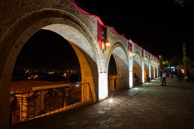 Gece gökyüzünün altında, Yanahuaras kemerleri Arequipa 'nın parlayan kalbini çerçeveler. Şehir ışıkları aşağıda parıldarken, sessiz volkanlar izliyor..