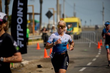 Demir Adam 70.3 Lima 'nın son turlarında koşan sporcular, sadece hayaller peşinde koşmakla kalmaz, aynı zamanda yaşarlar da. Gözyaşları, ter ve kırılmaz ruh bitiş çizgisine giden yolu işaretler..