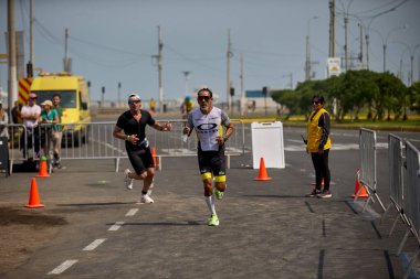 Demir Adam 70.3 Lima 'nın son turlarında koşan sporcular, sadece hayaller peşinde koşmakla kalmaz, aynı zamanda yaşarlar da. Gözyaşları, ter ve kırılmaz ruh bitiş çizgisine giden yolu işaretler..