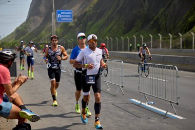 Demir Adam 70.3 Lima 'nın son turlarında koşan sporcular, sadece hayaller peşinde koşmakla kalmaz, aynı zamanda yaşarlar da. Gözyaşları, ter ve kırılmaz ruh bitiş çizgisine giden yolu işaretler..