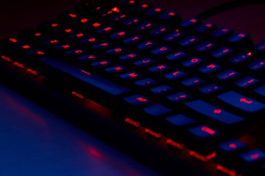 Renkli bir RGB mekanik oyun klavyesinin yakın çekimi canlı renklerle aydınlatılmış. Oyun ayarları için tasarlanmış modern bilgisayar aksesuarı, kişiselleştirilebilir arka ışıklandırma ve şık tasarım. 