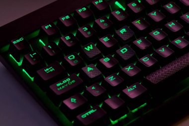 Renkli bir RGB mekanik oyun klavyesinin yakın çekimi canlı renklerle aydınlatılmış. Oyun ayarları için tasarlanmış modern bilgisayar aksesuarı, kişiselleştirilebilir arka ışıklandırma ve şık tasarım. 