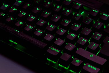 Renkli bir RGB mekanik oyun klavyesinin yakın çekimi canlı renklerle aydınlatılmış. Oyun ayarları için tasarlanmış modern bilgisayar aksesuarı, kişiselleştirilebilir arka ışıklandırma ve şık tasarım. 