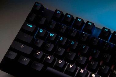 Renkli bir RGB mekanik oyun klavyesinin yakın çekimi canlı renklerle aydınlatılmış. Oyun ayarları için tasarlanmış modern bilgisayar aksesuarı, kişiselleştirilebilir arka ışıklandırma ve şık tasarım. 