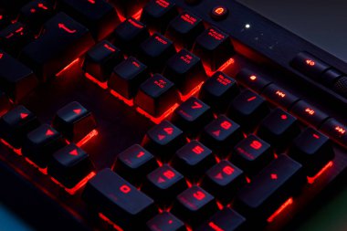 Renkli bir RGB mekanik oyun klavyesinin yakın çekimi canlı renklerle aydınlatılmış. Oyun ayarları için tasarlanmış modern bilgisayar aksesuarı, kişiselleştirilebilir arka ışıklandırma ve şık tasarım. 