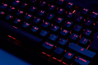 Renkli bir RGB mekanik oyun klavyesinin yakın çekimi canlı renklerle aydınlatılmış. Oyun ayarları için tasarlanmış modern bilgisayar aksesuarı, kişiselleştirilebilir arka ışıklandırma ve şık tasarım. 