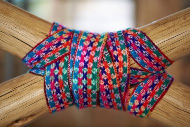 Geleneksel And örgü tekstil iki ahşap direği çapraz halatla bağlıyor. Canlı, renkli tasarım zengin kültür mirasını temsil eden karmaşık geometrik motifler içeriyor..