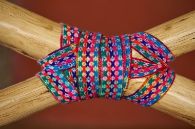 Geleneksel And örgü tekstil iki ahşap direği çapraz halatla bağlıyor. Canlı, renkli tasarım zengin kültür mirasını temsil eden karmaşık geometrik motifler içeriyor..