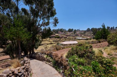 Taquile, taştan yollarla dolu huzurlu bir ada, teraslı tepeler, ve eski gelenekleri canlı tutan gururlu dokumacılar. Titicaca Gölü Peru.