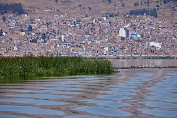 Titicacas Gölü 'nün sakin sularına yelken açmak. Arka planda Puno şehri var..