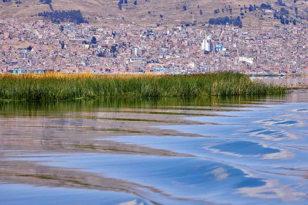 Titicacas Gölü 'nün sakin sularına yelken açmak. Arka planda Puno şehri var..