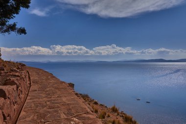 Taquile Adası 'nın yüksek yamaçlarından Titicaca Gölü bu yüksek irtifa harikasının muazzam güzelliğini ve dinginliğini gözler önüne seriyor. Ufka uzanan derin mavi sular ve And Işığı döküm.