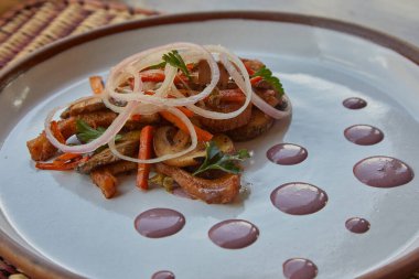 İçinde sotelenmiş mantarlar, yerli patatesler, havuçlar ve soğanlar bulunan rafine edilmiş bir Cusco tarzı yemek. Mor mısır redüksiyonu ustalıkla sunuluyor. Gelenek zarafetle buluşur.