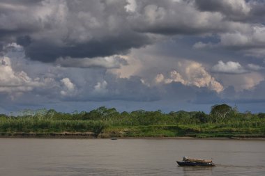 Pacaya Samiria Doğal Rezervi 'nin kalbinin derinliklerinde, Maran Nehri' ndeki yüksek fırtına bulutlarının altında yalnız bir tekne sürükleniyor. Loreto Peru.