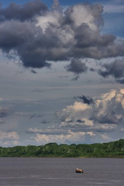 Pacaya Samiria Doğal Rezervi 'nin kalbinin derinliklerinde, Maran Nehri' ndeki yüksek fırtına bulutlarının altında yalnız bir tekne sürükleniyor. Loreto Peru.