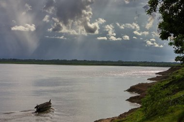 Pacaya Samiria Doğal Rezervi 'nin kalbinin derinliklerinde, Maran Nehri' ndeki yüksek fırtına bulutlarının altında yalnız bir tekne sürükleniyor. Loreto Peru.
