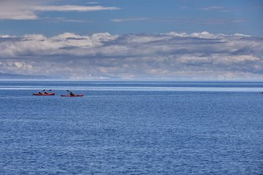 Bir grup deniz kayakçısı And Dağları 'nın engin, yüksek irtifa güzelliği ile çevrili Titicaca Gölü' nün derin mavi sularında huzur içinde süzülüyor. Puno Peru.