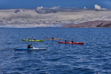 Bir grup deniz kayakçısı And Dağları 'nın engin, yüksek irtifa güzelliği ile çevrili Titicaca Gölü' nün derin mavi sularında huzur içinde süzülüyor. Puno Peru.