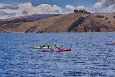 Bir grup deniz kayakçısı And Dağları 'nın engin, yüksek irtifa güzelliği ile çevrili Titicaca Gölü' nün derin mavi sularında huzur içinde süzülüyor. Puno Peru.