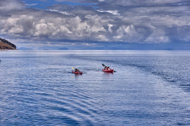 Bir grup deniz kayakçısı And Dağları 'nın engin, yüksek irtifa güzelliği ile çevrili Titicaca Gölü' nün derin mavi sularında huzur içinde süzülüyor. Puno Peru.