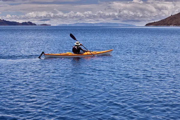 Bir grup deniz kayakçısı And Dağları 'nın engin, yüksek irtifa güzelliği ile çevrili Titicaca Gölü' nün derin mavi sularında huzur içinde süzülüyor. Puno Peru.