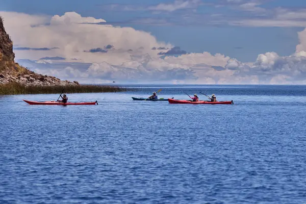 Bir grup deniz kayakçısı And Dağları 'nın engin, yüksek irtifa güzelliği ile çevrili Titicaca Gölü' nün derin mavi sularında huzur içinde süzülüyor. Puno Peru.