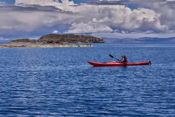 Bir grup deniz kayakçısı And Dağları 'nın engin, yüksek irtifa güzelliği ile çevrili Titicaca Gölü' nün derin mavi sularında huzur içinde süzülüyor. Puno Peru.