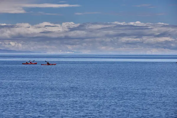 Bir grup deniz kayakçısı And Dağları 'nın engin, yüksek irtifa güzelliği ile çevrili Titicaca Gölü' nün derin mavi sularında huzur içinde süzülüyor. Puno Peru.