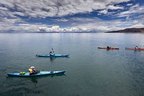 Bir grup deniz kayakçısı And Dağları 'nın engin, yüksek irtifa güzelliği ile çevrili Titicaca Gölü' nün derin mavi sularında huzur içinde süzülüyor. Puno Peru.