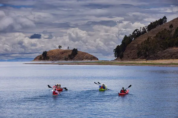 Bir grup deniz kayakçısı And Dağları 'nın engin, yüksek irtifa güzelliği ile çevrili Titicaca Gölü' nün derin mavi sularında huzur içinde süzülüyor. Puno Peru.