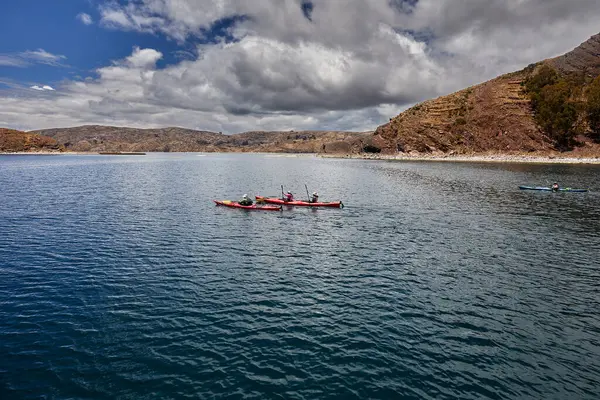 Bir grup deniz kayakçısı And Dağları 'nın engin, yüksek irtifa güzelliği ile çevrili Titicaca Gölü' nün derin mavi sularında huzur içinde süzülüyor. Puno Peru.