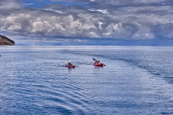 Bir grup deniz kayakçısı And Dağları 'nın engin, yüksek irtifa güzelliği ile çevrili Titicaca Gölü' nün derin mavi sularında huzur içinde süzülüyor. Puno Peru.