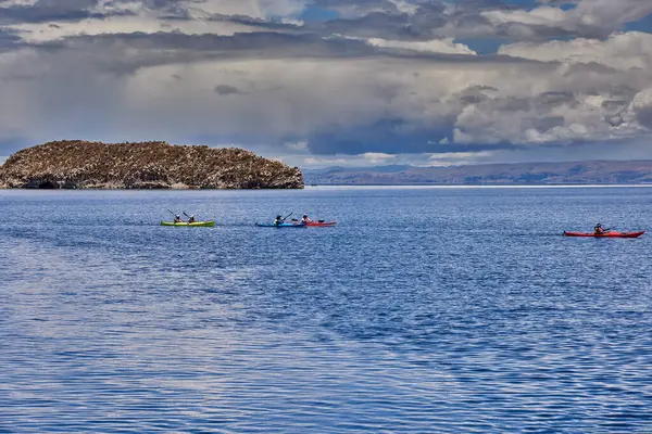 Bir grup deniz kayakçısı And Dağları 'nın engin, yüksek irtifa güzelliği ile çevrili Titicaca Gölü' nün derin mavi sularında huzur içinde süzülüyor. Puno Peru.