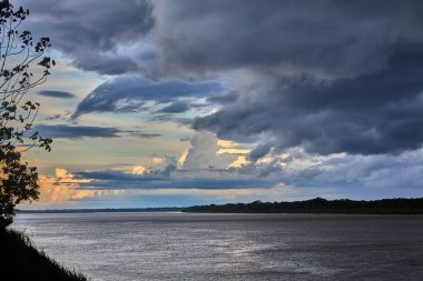 Gökyüzü güçlü Amazon fırtına bulutlarının üzerinde kükrer, rüzgarlar yükselir ve doğa bize ormanı kimin yönettiğini hatırlatır. Iquitos sularının üzerinde dramatik bir an.