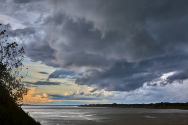 Gökyüzü güçlü Amazon fırtına bulutlarının üzerinde kükrer, rüzgarlar yükselir ve doğa bize ormanı kimin yönettiğini hatırlatır. Iquitos sularının üzerinde dramatik bir an.