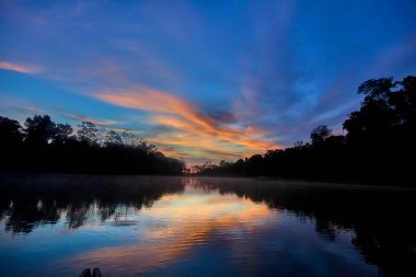 Pacaya Samiria 'nın aynalı suları üzerinde nefes kesici bir gün doğumu, sessizlik, sis ve renklerin doğanın en kutsal ayinlerinden birinde birleştiği yer. Peru yağmur ormanlarının derinliklerinde.