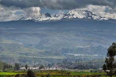 Chivay 'in çatılarından yükselen Hualca Hualca' nın karla kaplı zirvesi Colca Vadisi 'ni sessizce izliyor. Zamansız ve And topraklarına ve yerel bilgilere işlemiş.