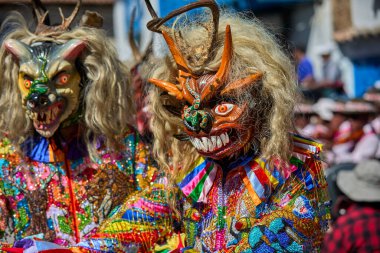 Şeytani maskeler ve akrobatik yeteneklerle, Saqras Paucartambo 'da dans ediyor, neşeli, alaycı ruhlar koruyor ve kışkırtıyor, enerji ve gerilim ekliyor. Bakire del Carmen