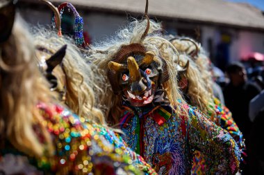 Şeytani maskeler ve akrobatik yeteneklerle, Saqras Paucartambo 'da dans ediyor, neşeli, alaycı ruhlar koruyor ve kışkırtıyor, enerji ve gerilim ekliyor. Bakire del Carmen