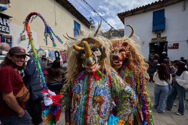 Şeytani maskeler ve akrobatik yeteneklerle, Saqras Paucartambo 'da dans ediyor, neşeli, alaycı ruhlar koruyor ve kışkırtıyor, enerji ve gerilim ekliyor. Bakire del Carmen
