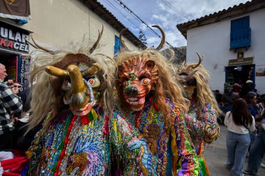 Şeytani maskeler ve akrobatik yeteneklerle, Saqras Paucartambo 'da dans ediyor, neşeli, alaycı ruhlar koruyor ve kışkırtıyor, enerji ve gerilim ekliyor. Bakire del Carmen