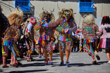 Şeytani maskeler ve akrobatik yeteneklerle, Saqras Paucartambo 'da dans ediyor, neşeli, alaycı ruhlar koruyor ve kışkırtıyor, enerji ve gerilim ekliyor. Bakire del Carmen