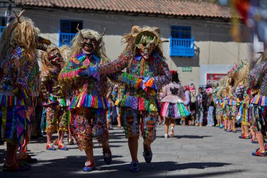 Şeytani maskeler ve akrobatik yeteneklerle, Saqras Paucartambo 'da dans ediyor, neşeli, alaycı ruhlar koruyor ve kışkırtıyor, enerji ve gerilim ekliyor. Bakire del Carmen